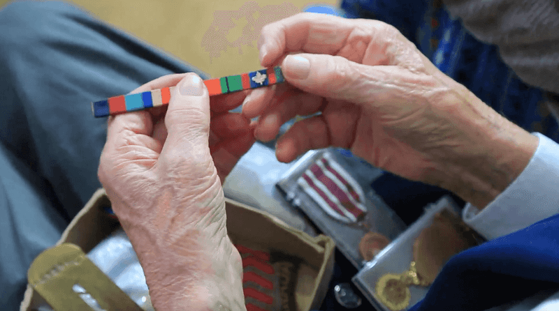Geoffrey Casson, one of the five western Manitoba veterans interviewed for the project, is holding a military ribbon in his hands.
